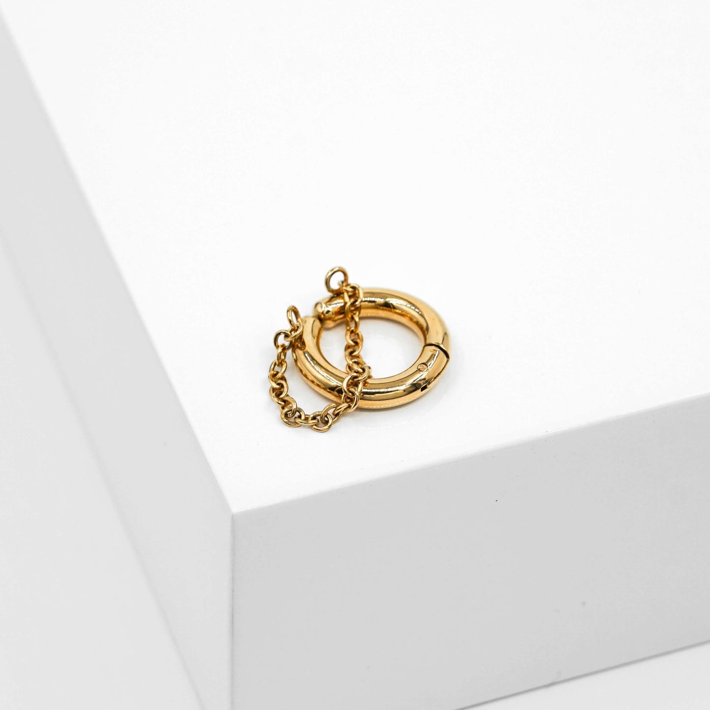 Kultainen korvarengas ja siinä kiinni oleva kultainen ketju.