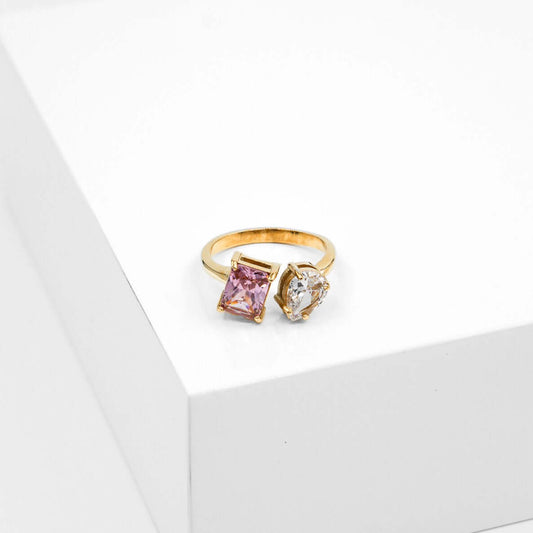 Kultainen sormus kahdella kirkkaalla ja vaaleanpunaisella erimuotoisella zirkonia kivellä.