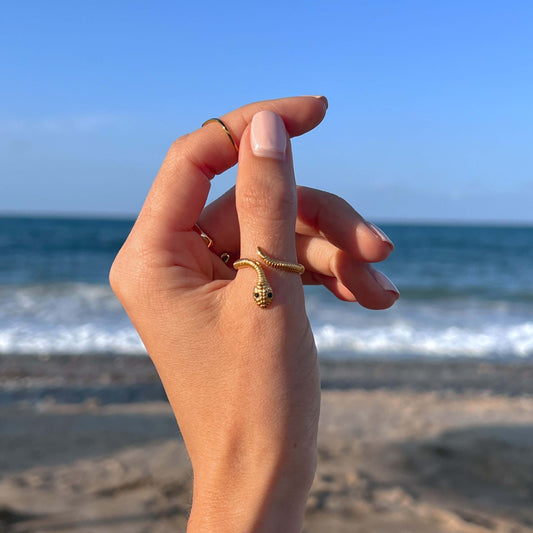 Sormus kuvattuna mallin sormessa. Sormus näyttää siltä kuin pieni käärme olisi kietoutunut sormen ympärille.